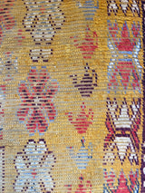 an antique moroccan rug with yellow tones and bright red accents