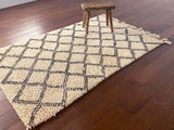 a vintage berber rug circa 1970 with a black trellis pattern on a neutral wool field