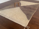 a vintage berber rug with two large taupe diamonds on a cream wool field