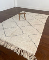 a large vintage berber rug with undyed wool field and a large black diamond pattern