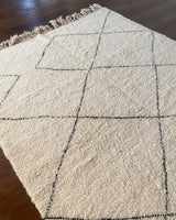 a large vintage berber rug with undyed wool field and a large black diamond pattern