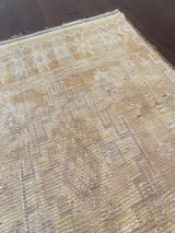 a vintage berber rug with light yellow field and geometric taupey grey accents