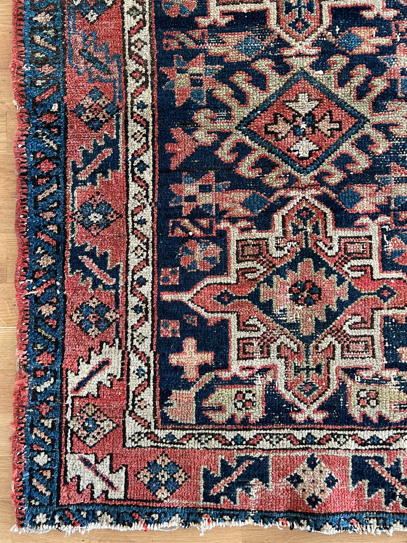a mini heriz rug with a navy blue field and coral accents