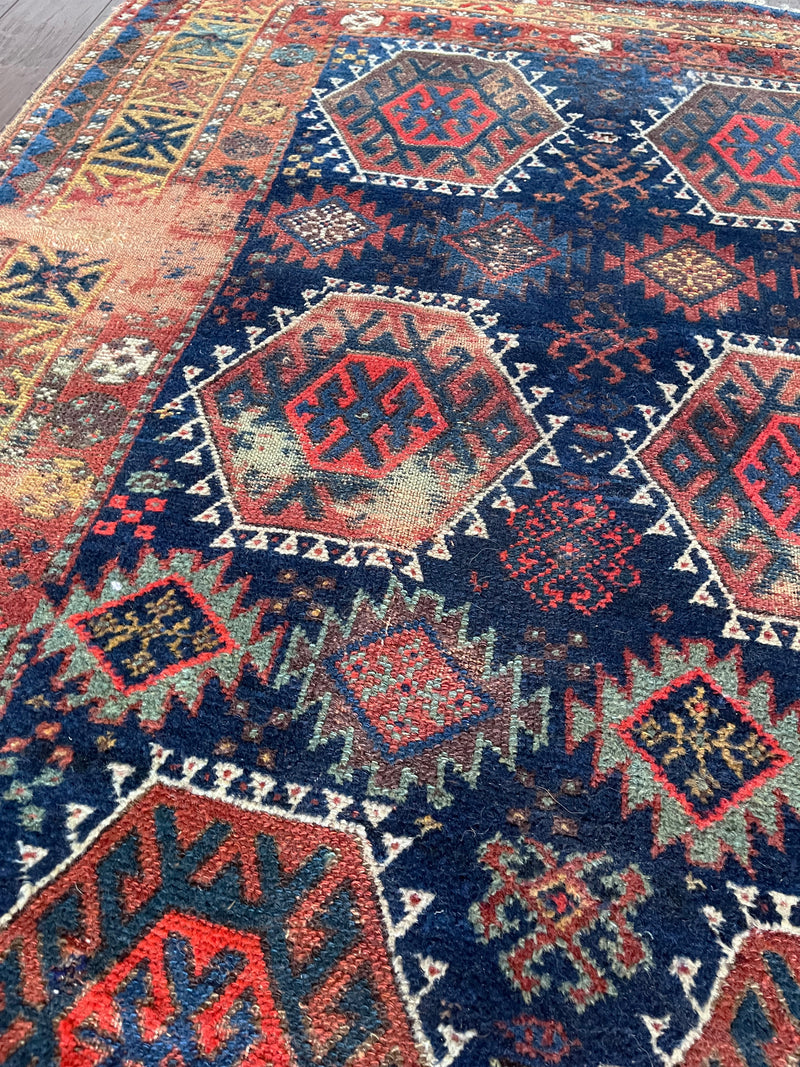 an antique kurdish rug with a royal blue field and a bright geometric pattern
