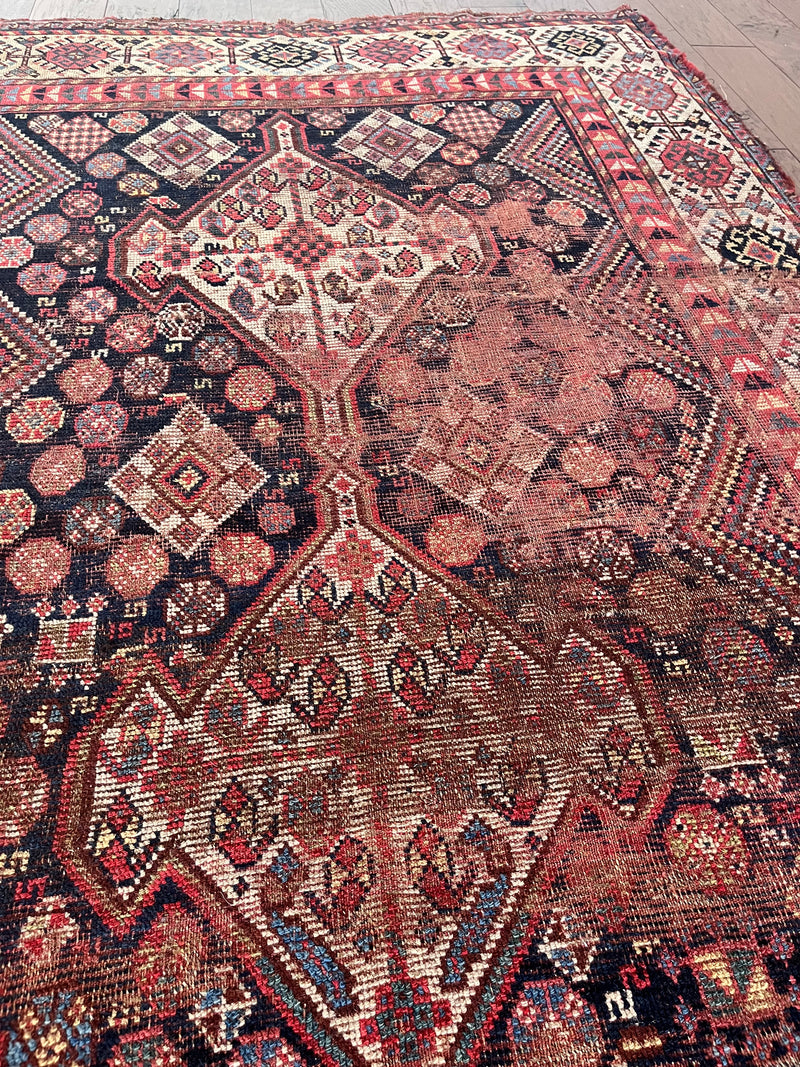 an antique shiraz qashqai rug with a dark blue field and red accents
