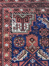 an antique baluch rug with a royal blue field and coral accents