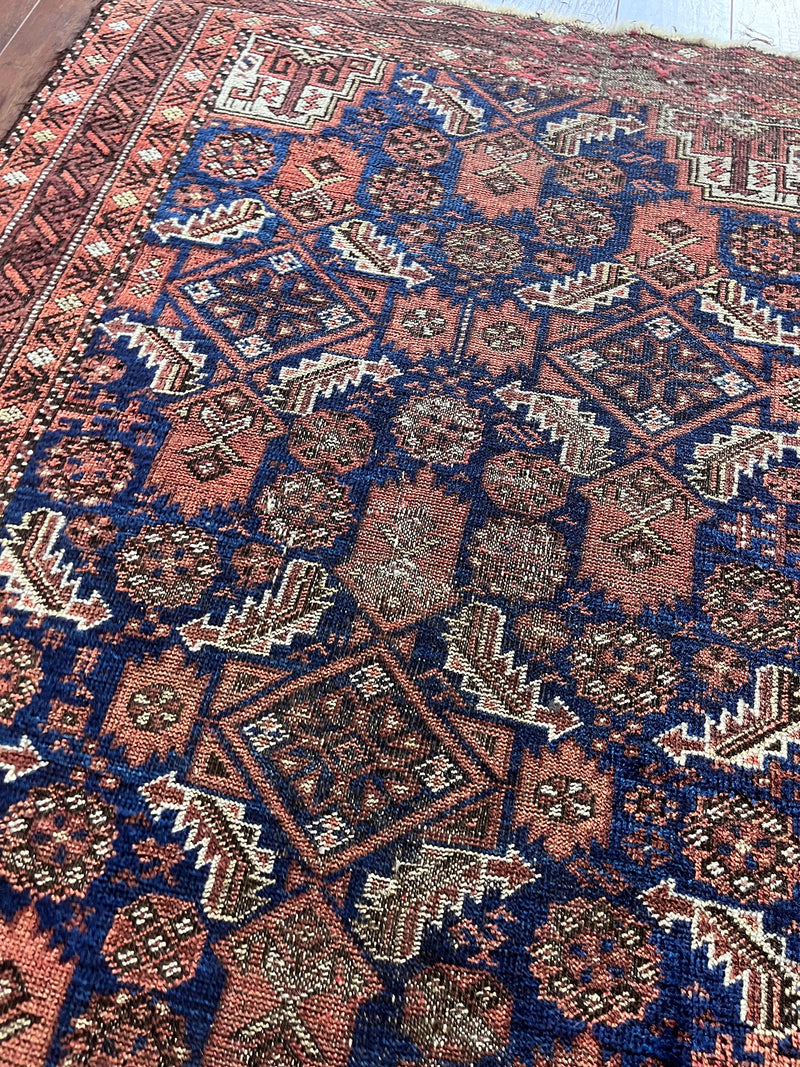 an antique baluch rug with a royal blue field and coral accents
