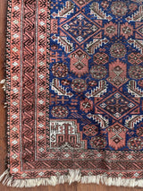 an antique baluch rug with a royal blue field and coral accents