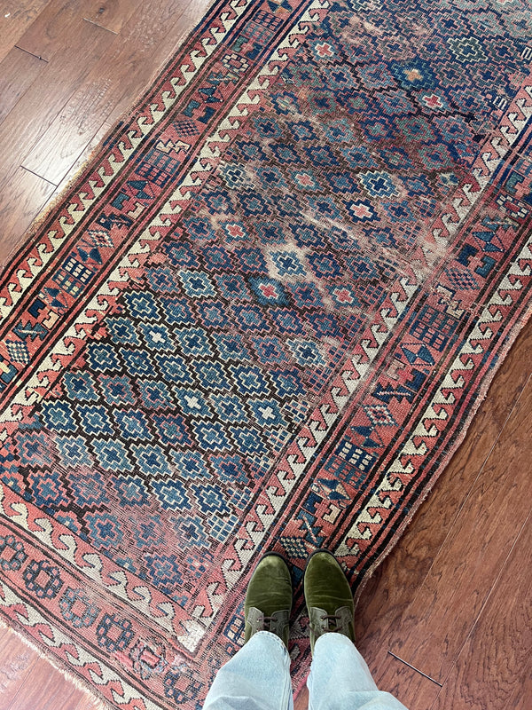  an antique kazak rug with pretty coral accents and a diamond pattern on a blue field