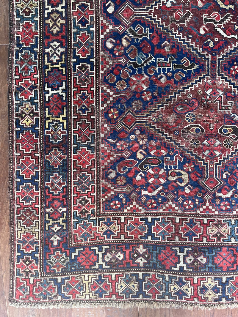 a large antique qashqai rug with a dark blue field, animal motifs and earthy accents
