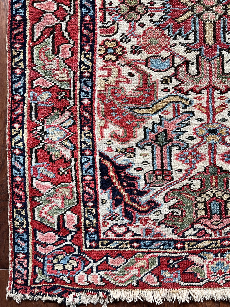 a mini antique heriz rug with a cream field, pink border and green accents