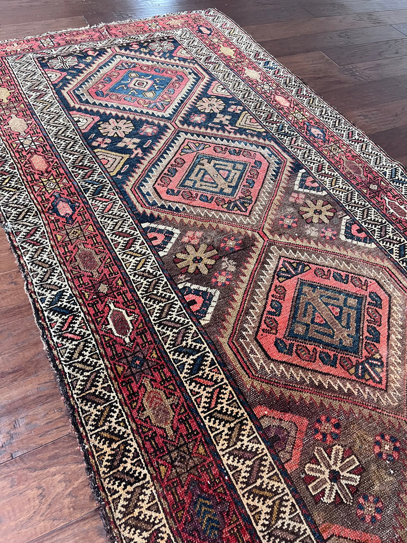 an antique malayer runner with warm rust and pink accents with blue undertones