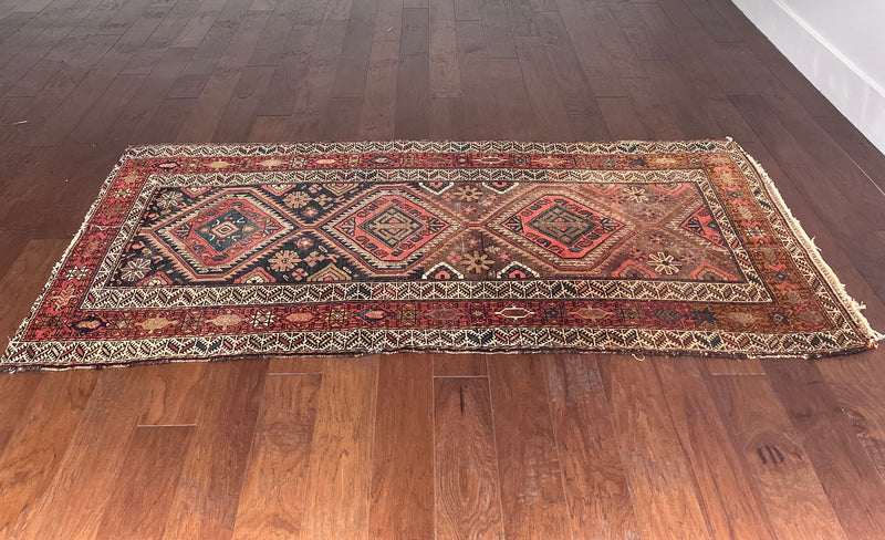 an antique malayer runner with warm rust and pink accents with blue undertones
