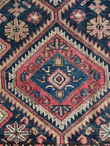 an antique malayer runner with warm rust and pink accents with blue undertones