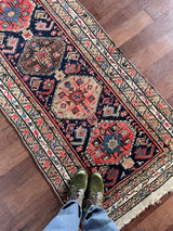 a mini north west persian runner with a dark blue field and neon pink accents