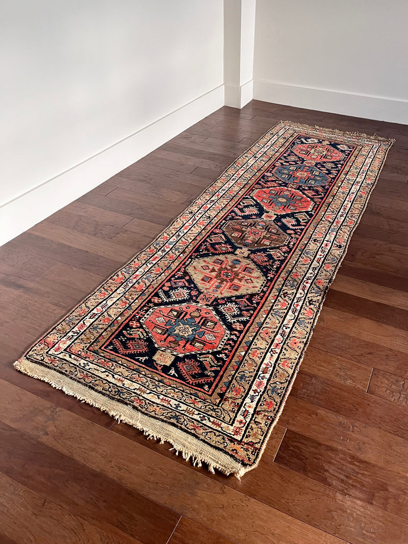 a mini north west persian runner with a dark blue field and neon pink accents