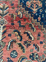 a mini shiraz rug with coral and navy blue accents