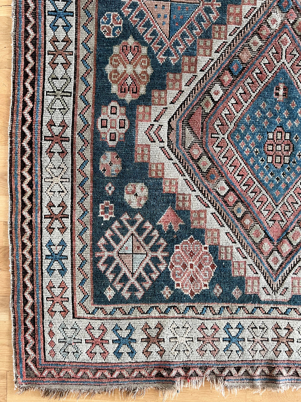 an antique caucasian shirwan rug with a blue palette and coral accents