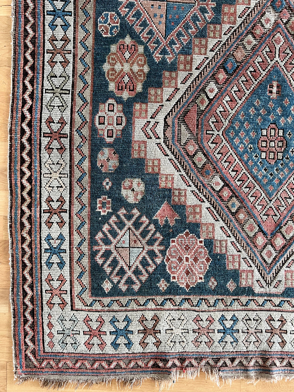 an antique caucasian shirwan rug with a blue palette and coral accents