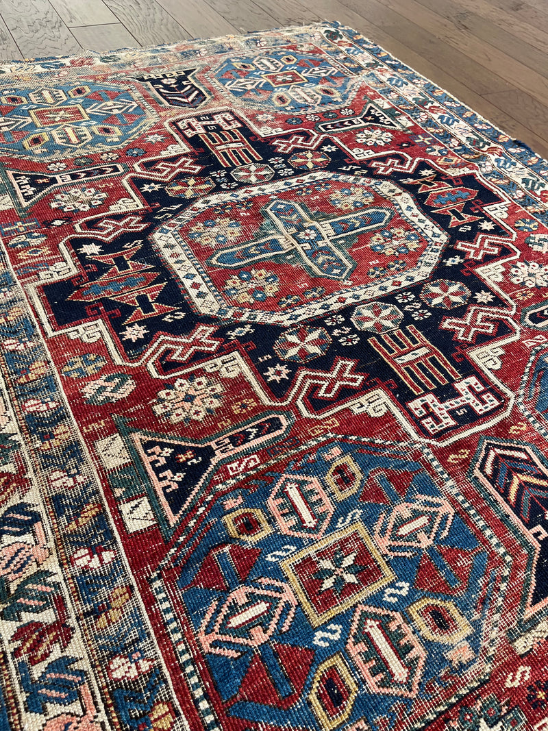 an antique caucasian shirwan rug with teal border, 4 blue corner medallions and a red field