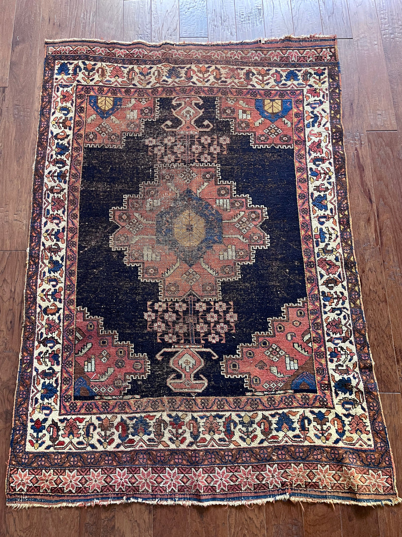 an antique afshar rug with a dark indigo field and earthy accents