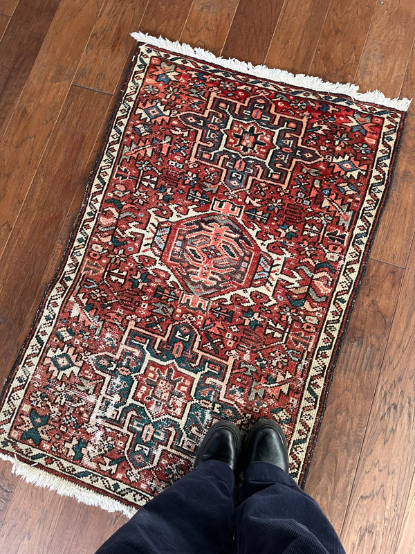 a vintage heriz karajah rug with pink and coral accents and two green medallions