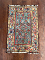 a mini antique rug with a blue field and earthy red accents