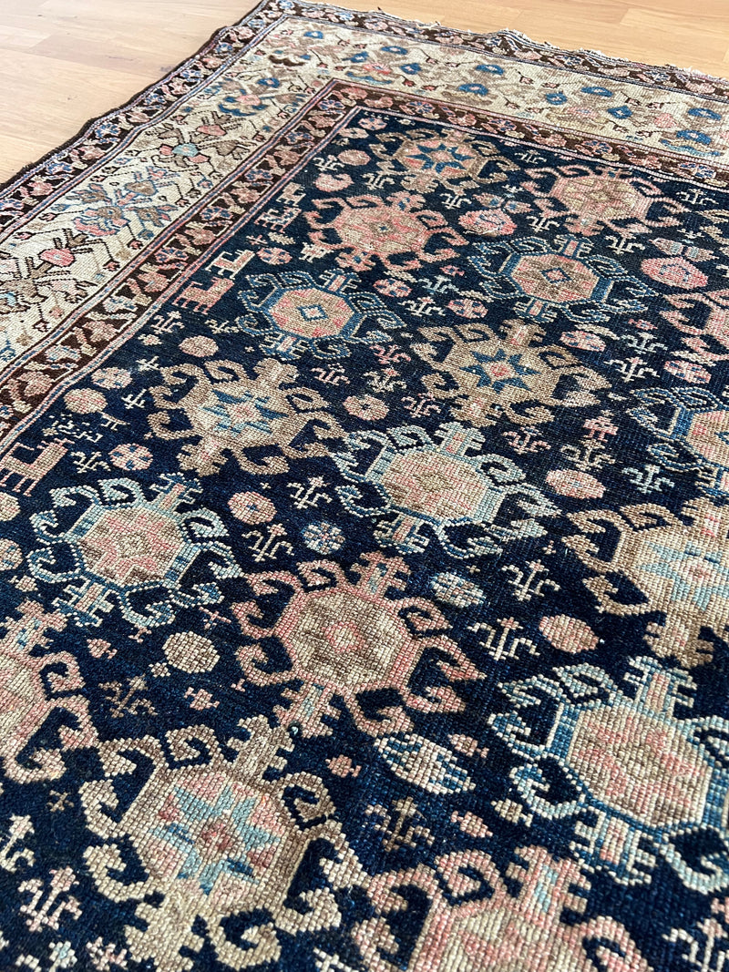 an antique malayer rug with midnight blue field and soft pink accents