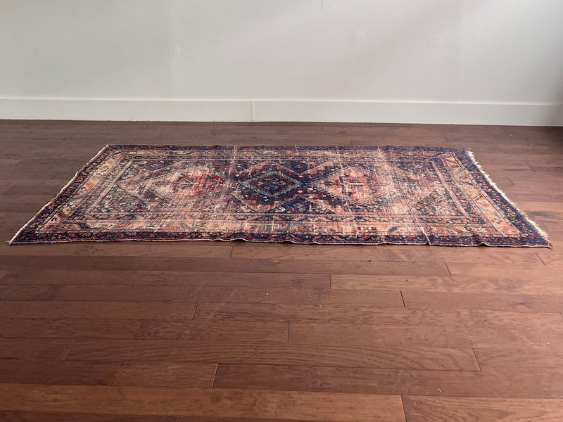 an antique shiraz rug with a coral, navy and red palette