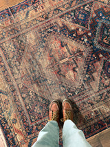 an antique shiraz rug with a coral, navy and red palette