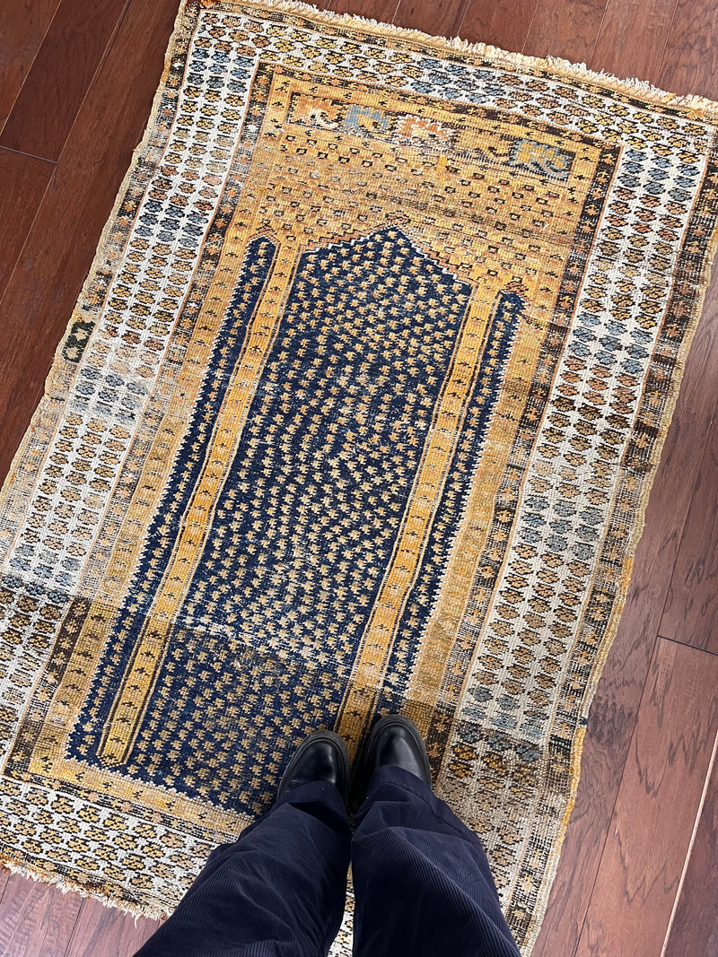 an antique turkish kula rug with mustard tones and dark blue accents
