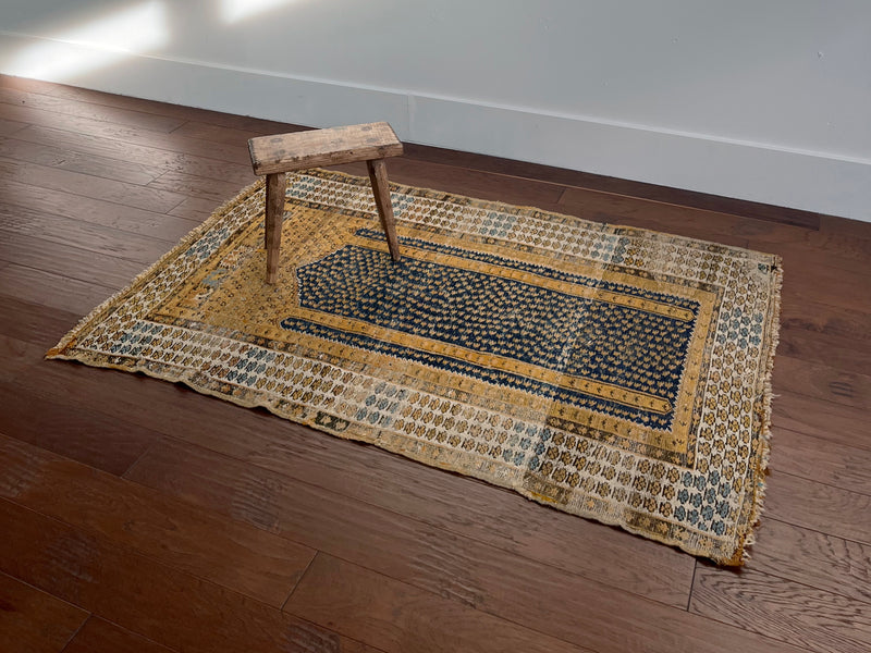 an antique turkish kula rug with mustard tones and dark blue accents